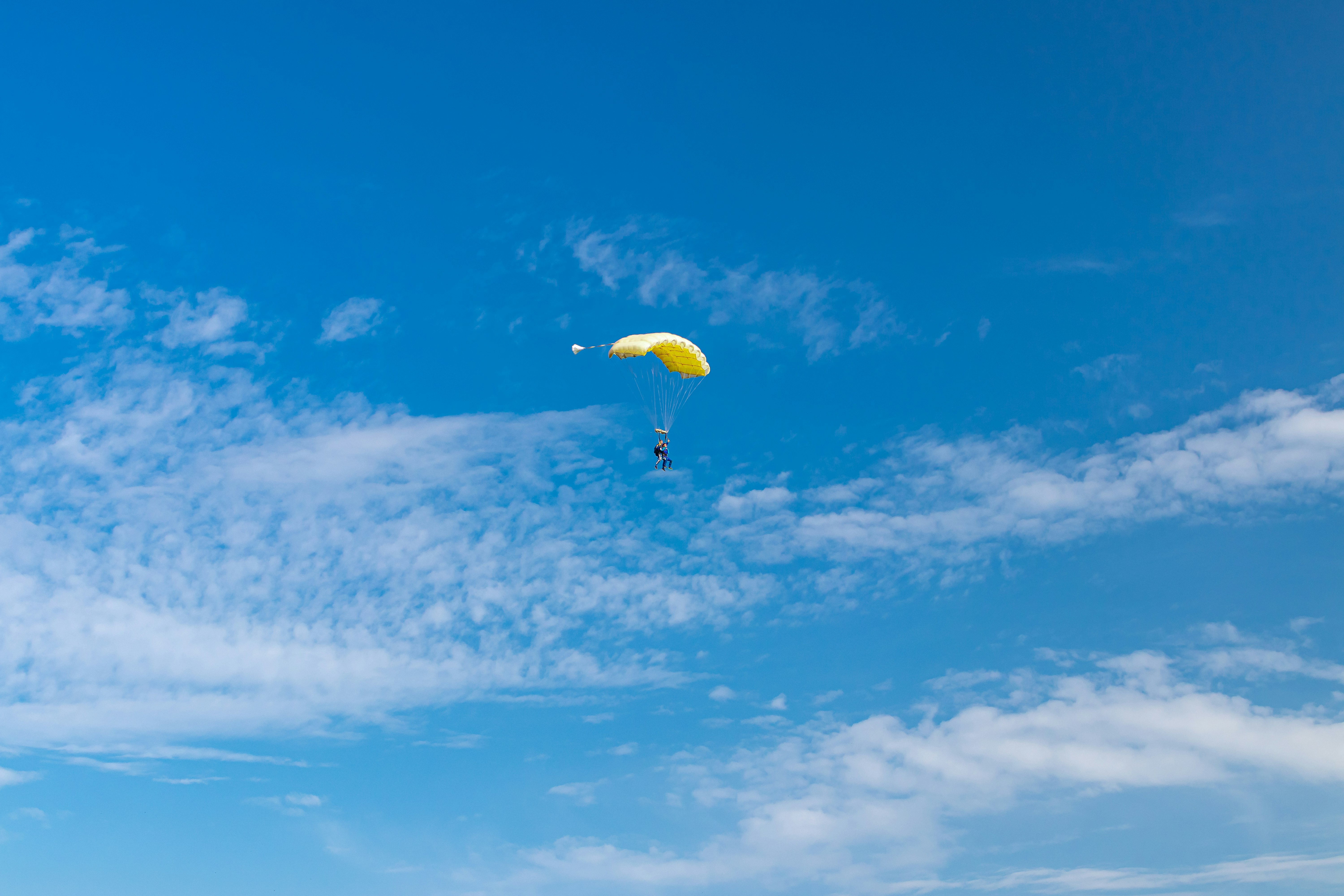 person in yellow parachute under blue sky during daytime